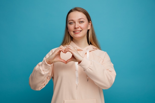 Sorridente giovane donna bionda facendo segno di amore