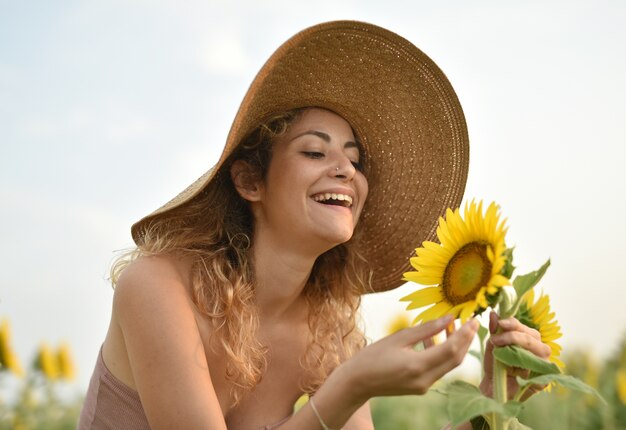 Sorridente giovane donna che indossa un cappello nel campo di girasoli