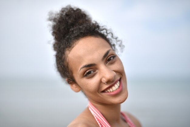 Sorridente giovane donna che indossa un costume da bagno in spiaggia - il concetto di felicità