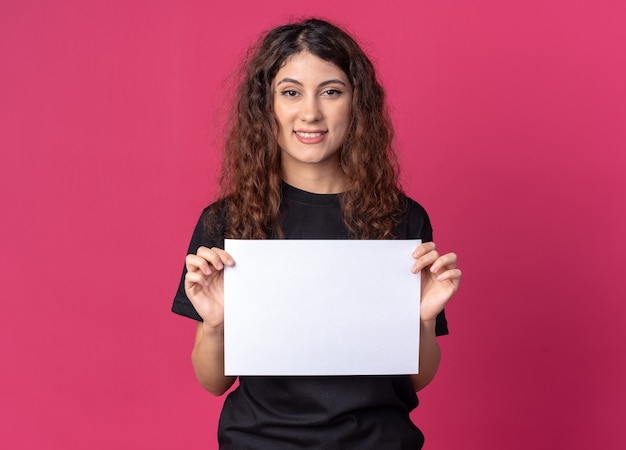 Sorridente giovane donna graziosa che tiene carta bianca