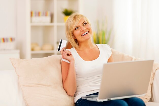 Sorridente giovane donna utilizzando laptop e tenendo la carta di credito