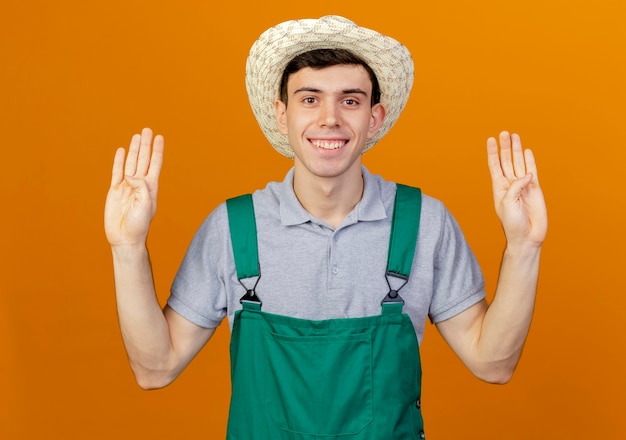 Sorridente giovane giardiniere maschio che indossa il cappello di giardinaggio gesti otto con le dita