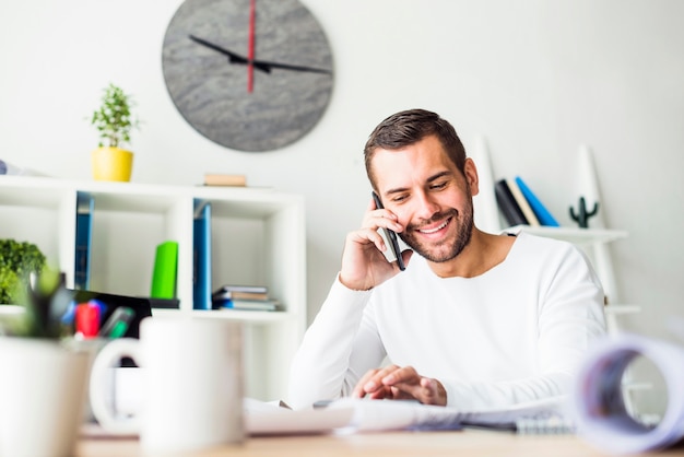 Sorridente giovane imprenditore parlando su smartphone