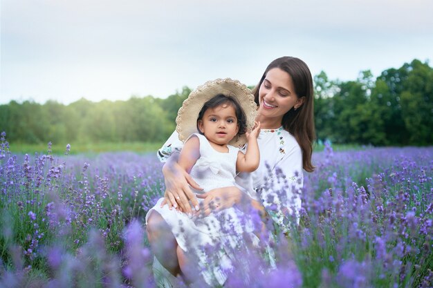 Sorridente giovane madre in posa con il bambino nel campo di lavanda