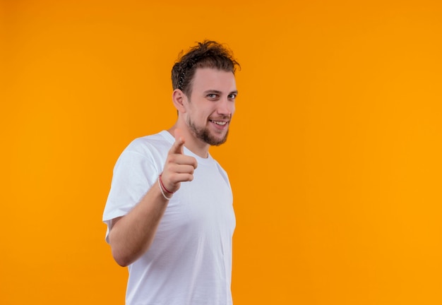 Sorridente giovane ragazzo che indossa la maglietta bianca che mostra il gesto su sfondo arancione isolato