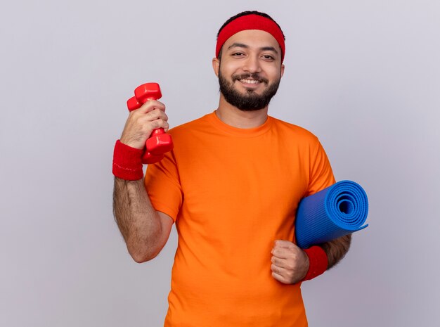 Sorridente giovane sportivo da indossare fascia e polsino tenendo i manubri