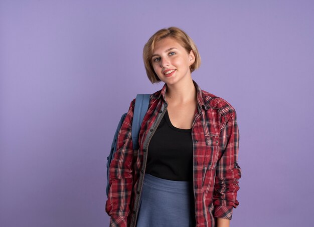 Sorridente giovane studentessa slava che indossa uno zaino guarda la telecamera