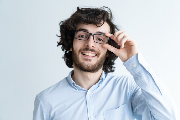 Sorridente giovane uomo dai capelli scuri, regolando gli occhiali