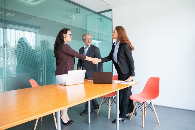 Sorridente imprenditori in piedi e riunione nella sala conferenze