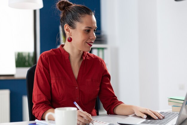 Sorridente imprenditrice che legge i dati dallo schermo del laptop