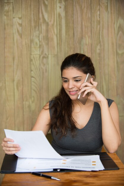 Sorridente imprenditrice parlando sul telefono e lavorando