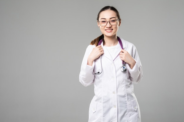 Sorridente medico donna asiatica con le braccia incrociate contro il muro bianco