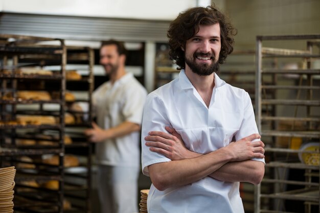 Sorridente panettiere in piedi con le mani incrociate