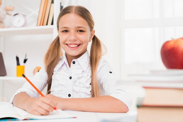 Sorridente ragazza bionda scuola elementare facendo i compiti