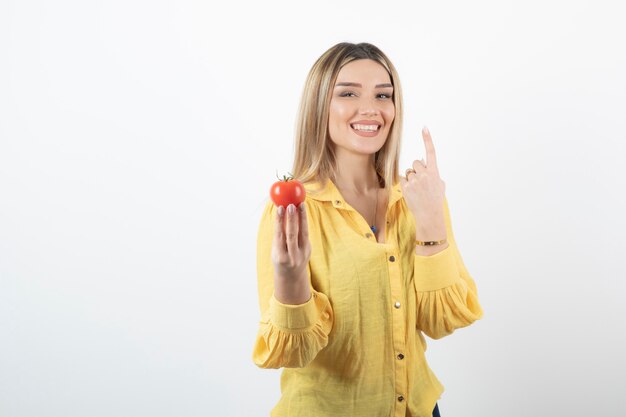 Sorridente ragazza con pomodoro rosso un attaccare la sua lingua su bianco.