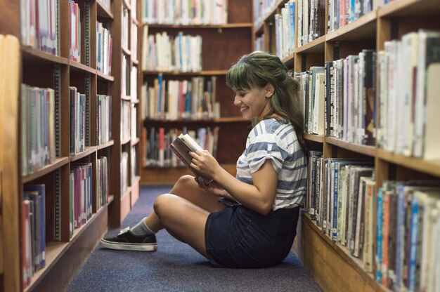 Sorridente ragazza lettura in biblioteca
