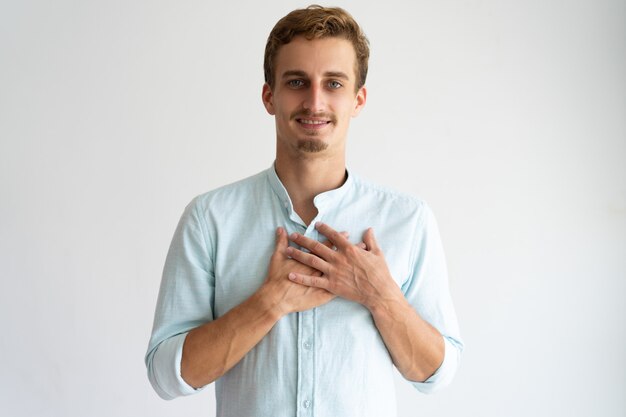 Sorridente ragazzo biondo amichevole che esprime gratitudine.