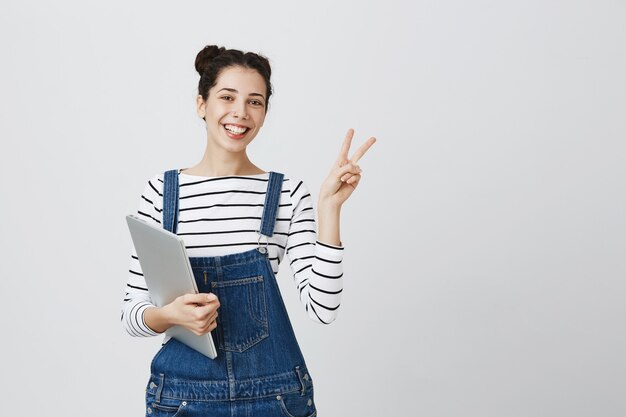 Sorridente simpatico giovane programmatore, ragazza adolescente inizia a codificare, tenendo il laptop e guardando soddisfatto