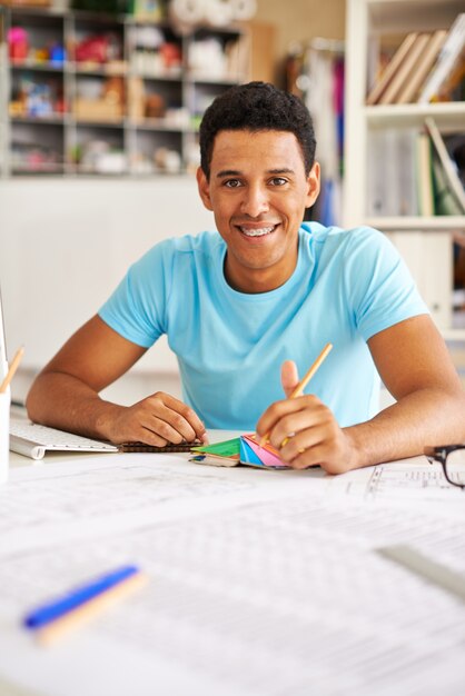 Sorridente studente con una matita e una tavolozza di colori