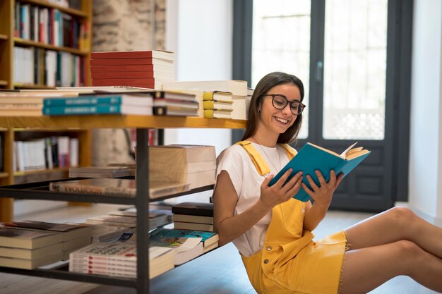 Sorridente studentessa adolescente con il libro sul pavimento