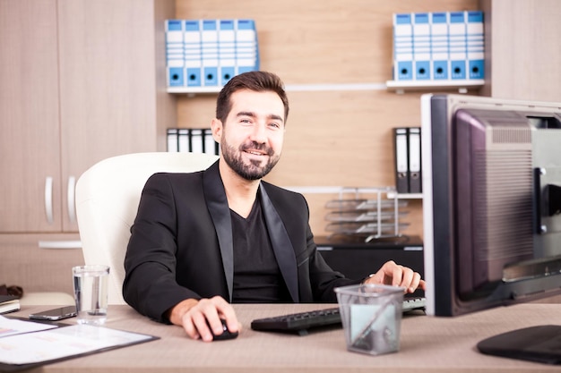 Sorridente uomo d'affari che lavora nel suo ufficio. Imprenditore in ambiente professionale