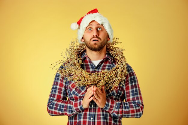 Sorridente uomo di Natale che indossa un cappello da Babbo Natale in preghiera su sfondo arancione