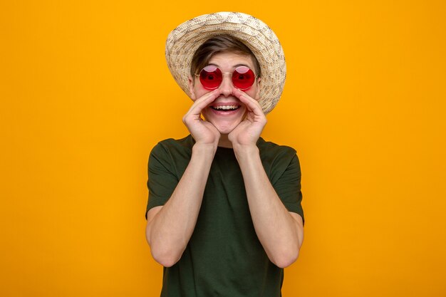 Sorridere chiamando un giovane bel ragazzo che indossa un cappello con gli occhiali