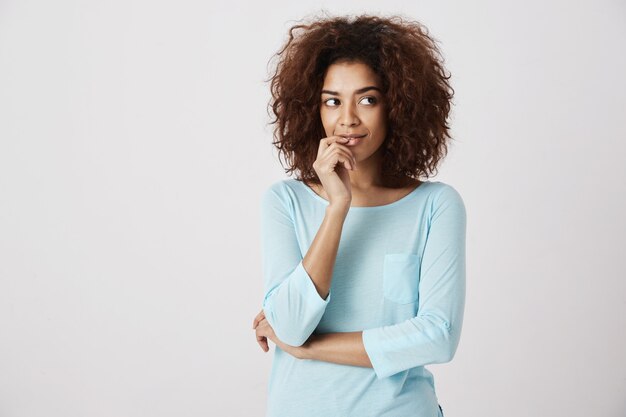 Sorridere di pensiero della ragazza africana vaga. muro bianco. Copia spazio.