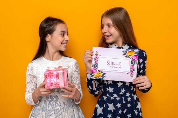 Sorridere guardandosi due bambine durante la felice festa della donna che tengono presente con un biglietto di auguri