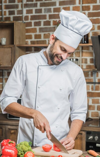 Sorridere verdure professionali di taglio del cuoco nella cucina