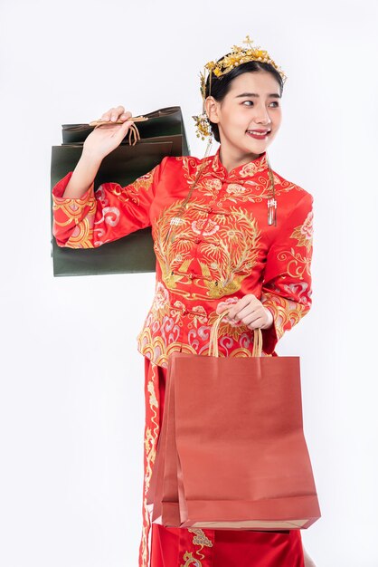 Sorriso del vestito di Cheongsam di usura della donna con il sacchetto di carta dallo shopping nel nuovo anno cinese