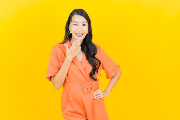 Sorriso della bella giovane donna asiatica del ritratto con azione sul giallo
