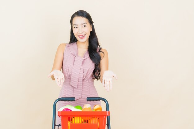Sorriso della bella giovane donna asiatica del ritratto con il cestino della drogheria dal supermercato