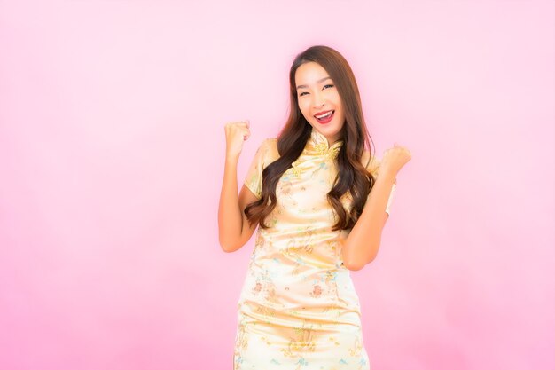 Sorriso della bella giovane donna asiatica del ritratto nell'azione con il concetto cinese del nuovo anno sulla parete di colore rosa