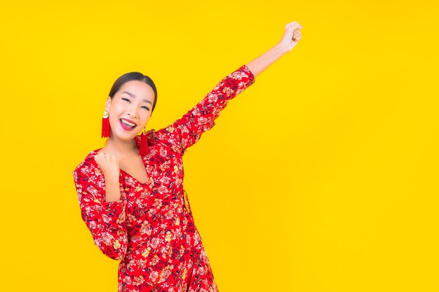 Sorriso della bella giovane donna asiatica del ritratto nell'azione nel concetto cinese del nuovo anno sulla parete di colore