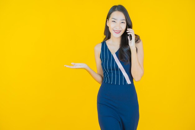 Sorriso di bella giovane donna asiatica del ritratto con il telefono cellulare astuto acceso