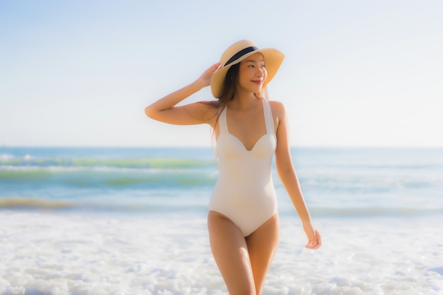 Sorriso felice della bella giovane donna asiatica del ritratto intorno alla spiaggia dell'oceano del mare