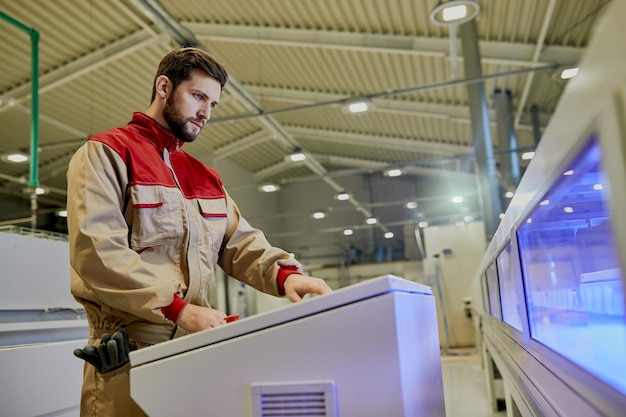 Sotto la vista di un lavoratore che utilizza una macchina per la lavorazione del legno automatizzata presso l'impianto di produzione