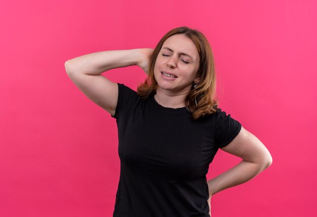 Sottolineato giovane donna casual con le mani dietro la testa e dietro la schiena sulla parete rosa isolata