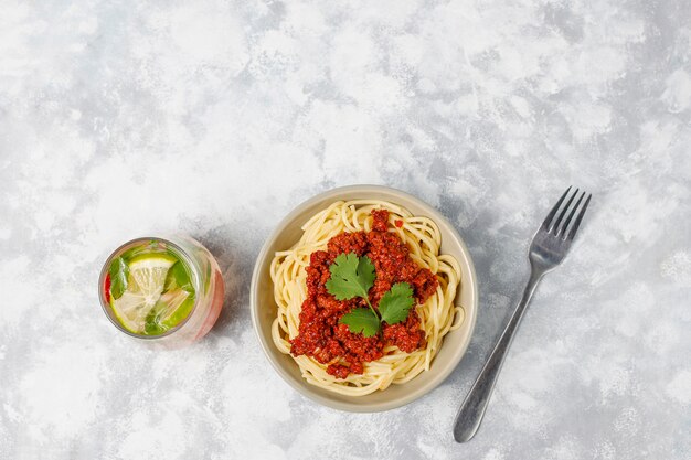 Spaghetti alla bolognese e limonata su cemento grigio