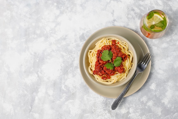 Spaghetti alla bolognese e limonata su cemento grigio