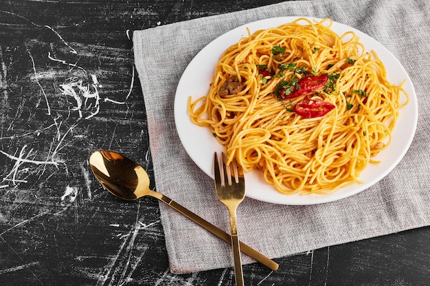 Spaghetti alle erbe e verdure in un piatto bianco, vista dall'alto