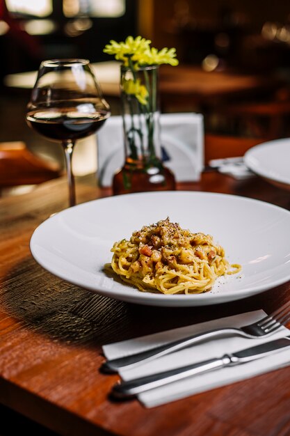 Spaghetti con carne in salsa cremosa guarnita con parmigiano grattugiato