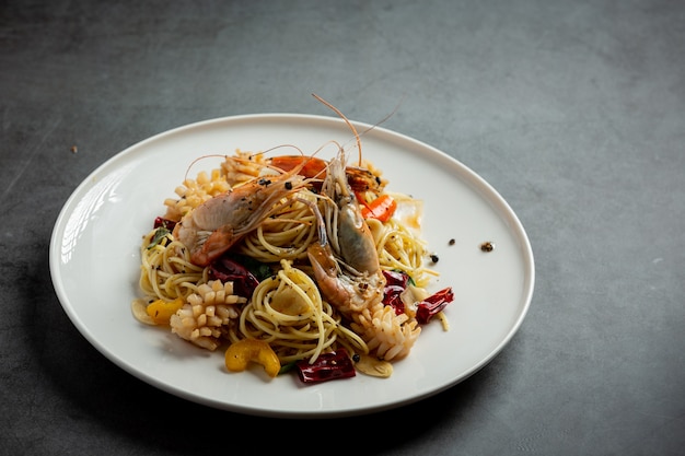 Spaghetti con frutti di mare misti piccanti su fondo scuro