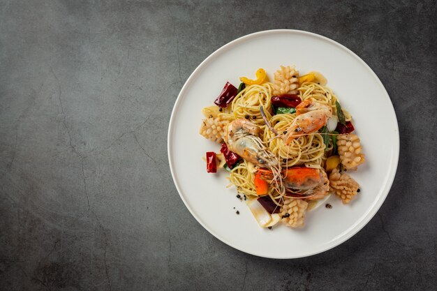 Spaghetti con frutti di mare misti piccanti su fondo scuro