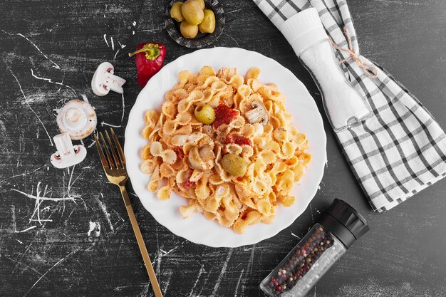 Spaghetti con ingredienti misti in un piatto bianco, vista dall'alto.