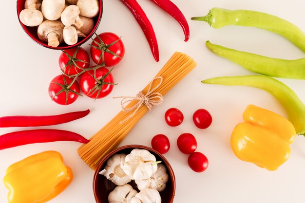 spaghetti con ingredienti per cucinare la pasta su una superficie bianca vista dall'alto