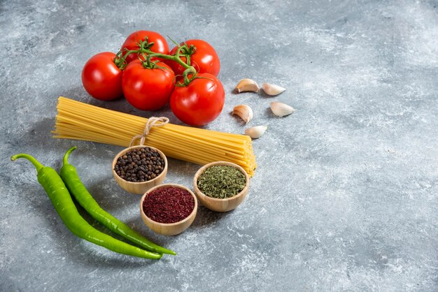 Spaghetti crudi con verdure su fondo di marmo.