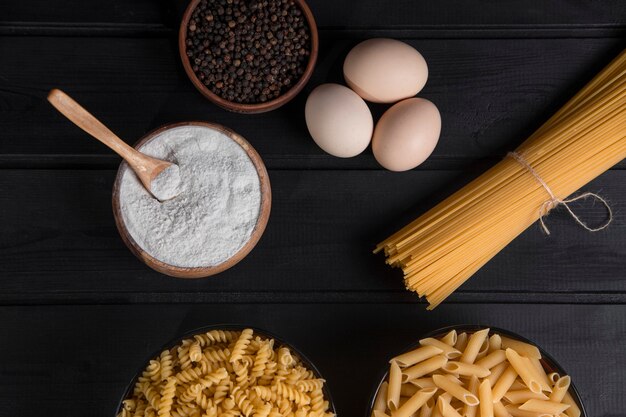 Spaghetti crudi legati con corda e pepe in grani posti su un tavolo di legno. Foto di alta qualità