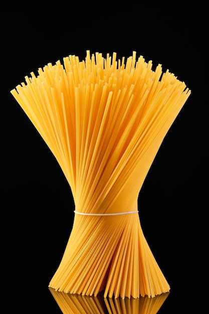 Spaghetti crudi legati in un covone si ergono su un vetro scuro su sfondo nero spaghetti italiani integrali